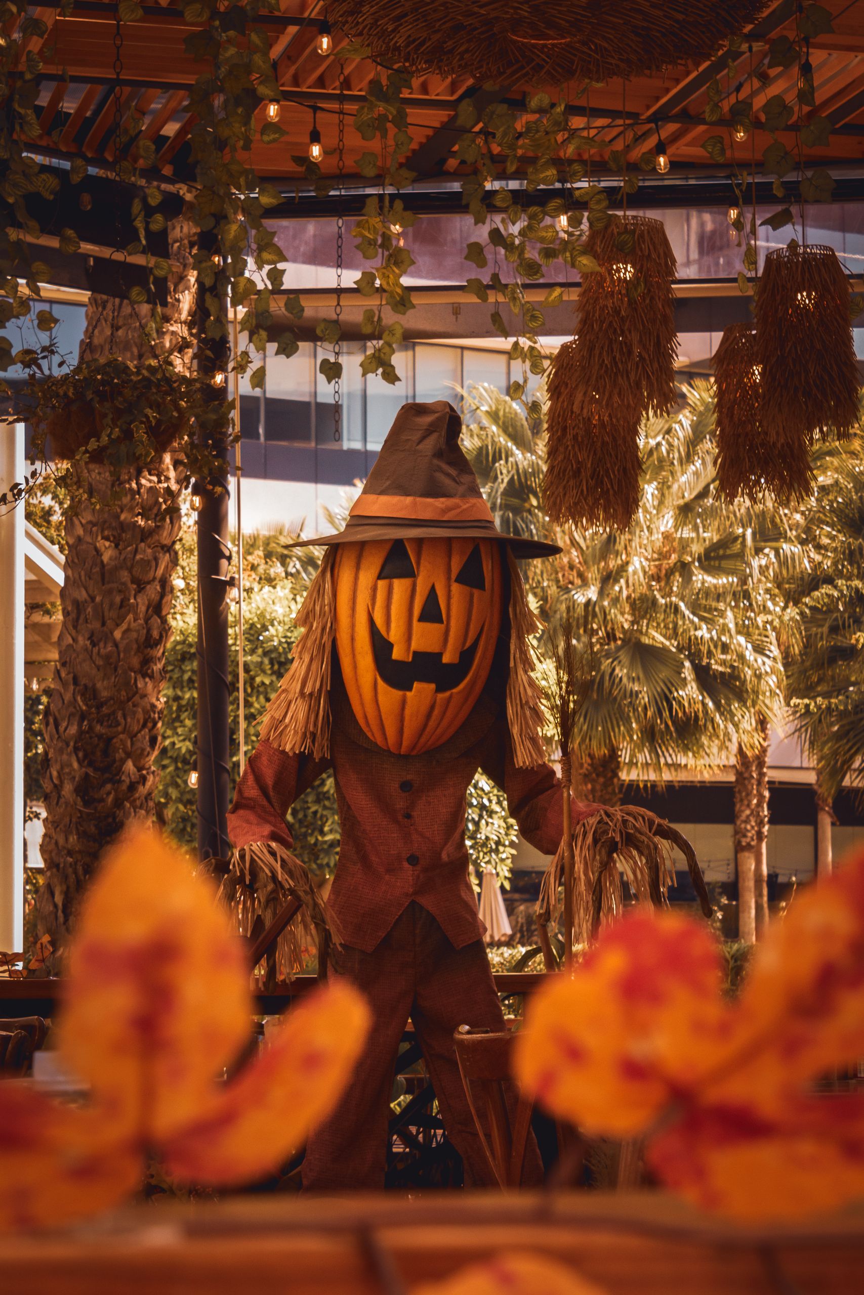 A festive Halloween scarecrow with a pumpkin head in a decorated garden setting, capturing the autumn spirit.
