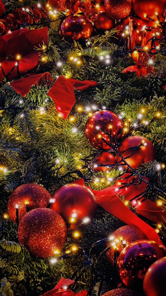 Close-up of vibrant red Christmas baubles and sparkling lights on a festive tree in Bucharest, Romania.